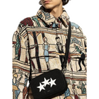 FLEX SHOP Amiri black messenger bag with white three-star detailing worn across the body by a model