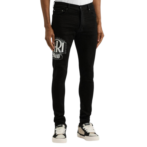 FLEX SHOP Amiri black skinny jeans with crystal Hollywood logo, distressed denim, and tapered fit on a male model.