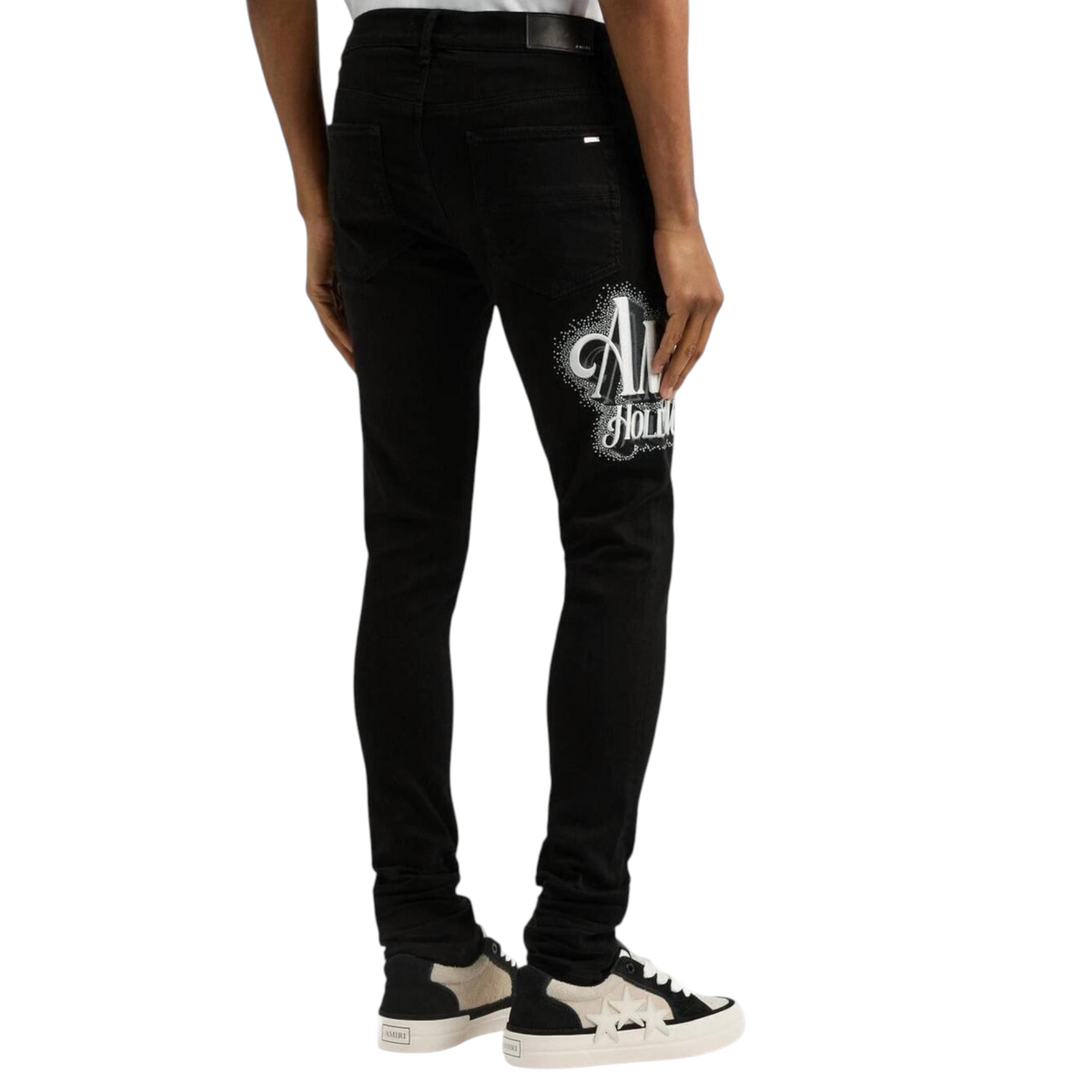 FLEX SHOP Amiri black skinny jeans with crystal Hollywood logo on the back thigh, worn by a model in sneakers.